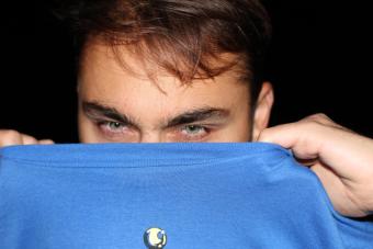 Christian Meola Headshot, lower half of face covered by blue fabric, brown hair and blue eyes, black background